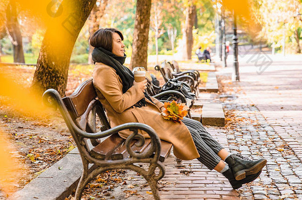 <strong>女人</strong>坐着板凳上秋天城市公园喝咖啡