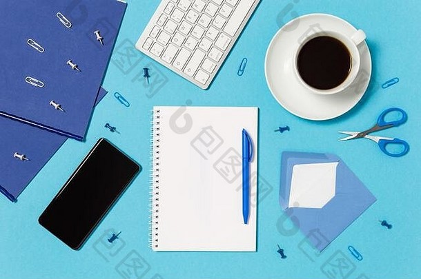 有创意的工作空间键盘咖啡杯记事本笔移动电话信封剪刀针剪辑蓝色的白色首页办公室概念