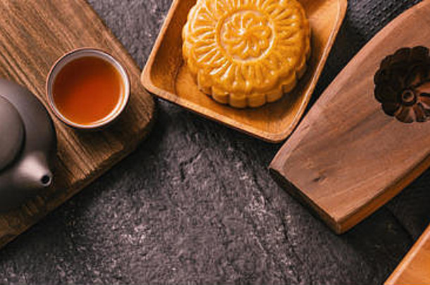 <strong>中</strong>秋节日传统的食物概念美丽的月亮蛋糕黑色的板岩表格茶糕点模具花前视图平躺复制空间