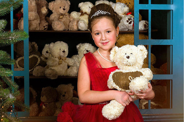 可爱的女孩穿着郁郁葱葱的红色的礼服拥抱豪华的熊窗口玩具庆祝活动情人节一天