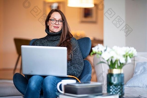 拍摄微笑年轻的女人移动PC坐着<strong>椅</strong>子工作首页