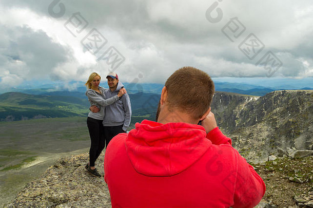爱的夫妇站山接吻前面摄影师背景谷沐浴阳光山蓝色的湖