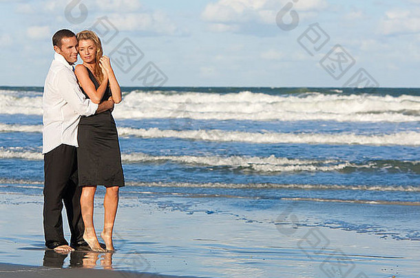 年轻的男人。女人拥抱浪漫的夫妇站海海滩蓝色的天空