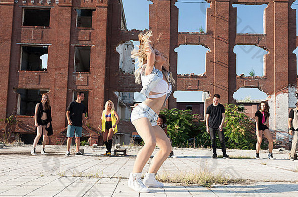 年轻的女孩臀部跳跳舞城市广场朋友支持自然光太阳高层建筑