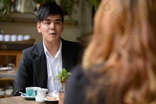 年轻的亚洲业务夫妇会说话的咖啡商店