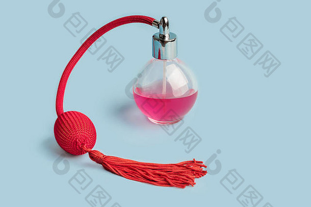 明亮的粉红色的香水玻璃透明的瓶红色的古董风格喷雾器安全气囊流苏柔和的婴儿蓝色的背景