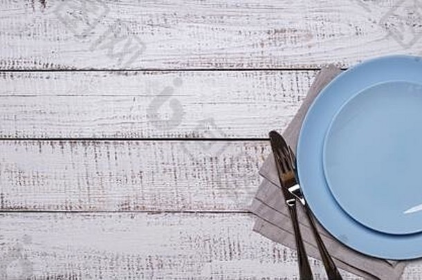 蓝色的盘子餐巾餐具白色木背景视图