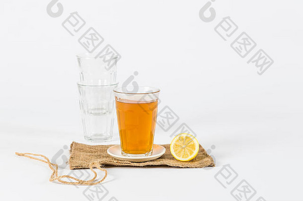 玻璃茶空眼镜一半柠檬小黄麻袋工作室设置白色背景