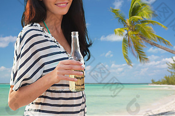关闭微笑年轻的女人喝海滩