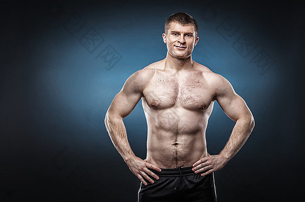 运动健康的肌肉发达的男人。孤立的黑暗蓝色的背景