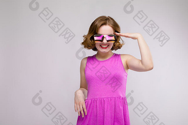 迷人的年轻的女孩粉红色的衣服灰色的背景快乐的女孩广场眼镜女孩把手头