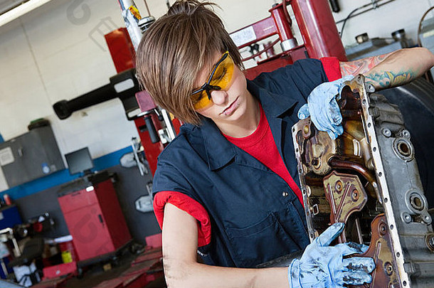 年轻的女机械师工作汽车机械部分车间