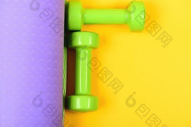 杠铃小大小瑜伽席关闭健康的形状体育运动概念哑铃使光绿色塑料黄色的紫色的背景前视图塑造健身设备