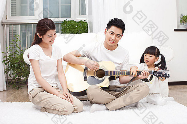 年轻的家庭玩吉他生活房间