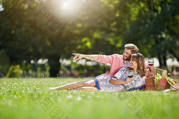 照片年轻的夫妇放松公园喝红色的酒