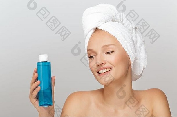 肖像快乐的女孩化妆白色毛巾头持有蓝色的化妆品瓶手幸福的灰色的背景