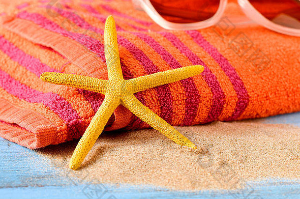 特写镜头黄色的海星桩沙子一对太阳镜橙色海滩毛巾乡村蓝色的木制