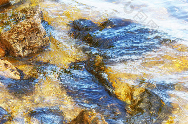 石头河波运行海岸线夏天日落太阳的射线反映了水