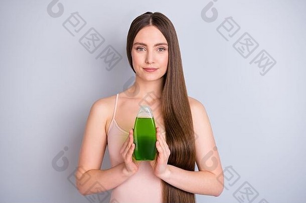 照片美丽的夫人长柔滑的发型持有绿色瓶新奇的事物出售专业护理治疗洗发水过来这里穿米色单线态孤立的灰色