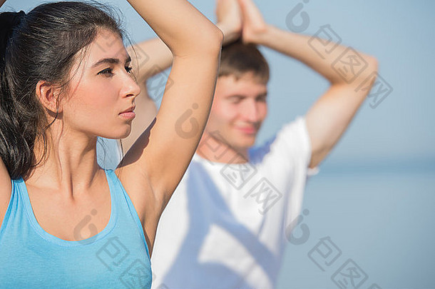 年轻的夫妇伸展运动瑜伽练习海背景