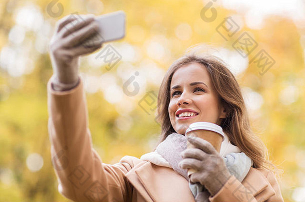 女人采取自拍智能手机秋天公园