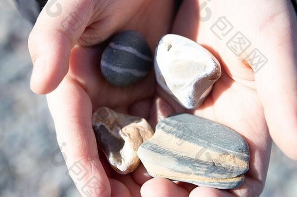 女人的手持有石头自然石头海滩