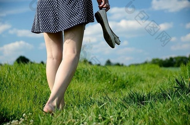 女走草光着脚年轻的女人享受户外走自然绿色字段蓝色的天空