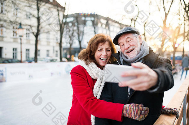 高级夫妇智能手机走城市冬天