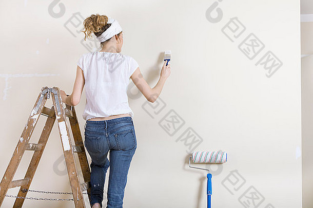 女人画笔手站梯绘画墙