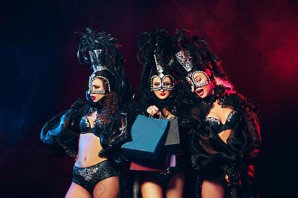 集团年轻的快乐微笑美丽的女舞者狂欢节礼服摆姿势购物袋黑色的工作室背景