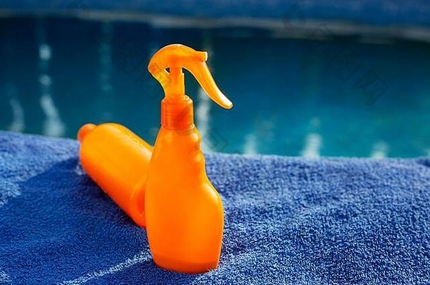 化妆品防晒霜产品集橙色瓶太阳保护身体奶油蓝色的毛巾游泳池皮肤护理保护