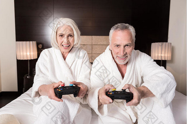 快乐的岁的夫妇玩游戏控制台床上
