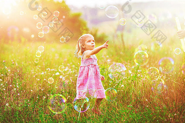 有趣的女孩捕捉肥皂泡沫夏天自然快乐童年概念