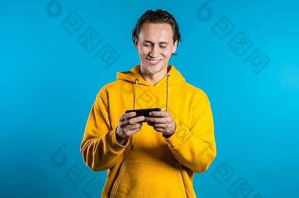 男人。短信发短信应用程序智能手机英俊的年轻的的家伙冲浪互联网移动电话蓝色的工作室背景