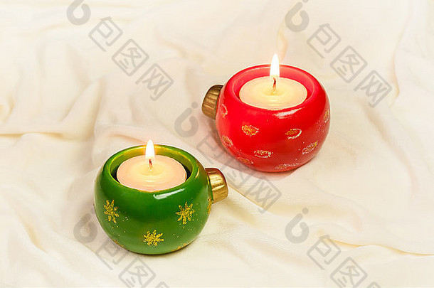 一对圣诞节点缀形状的出现蜡烛集奶油彩色的丝绸布圣诞节背景