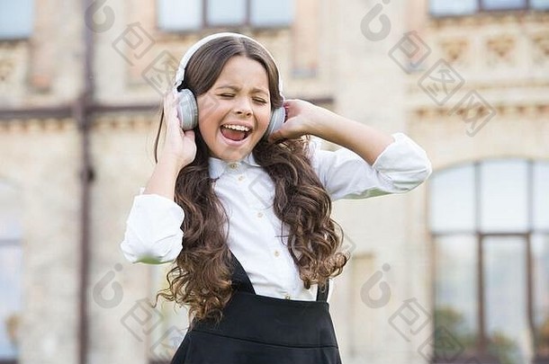 孩子音乐打破女孩耳机漂亮的女孩穿优雅的统一的回来学校现代教育技术孩子唱校园梦想歌手