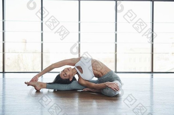 练习伸展运动欧洲年轻的浅黑肤色的女人瑜伽房间大窗户