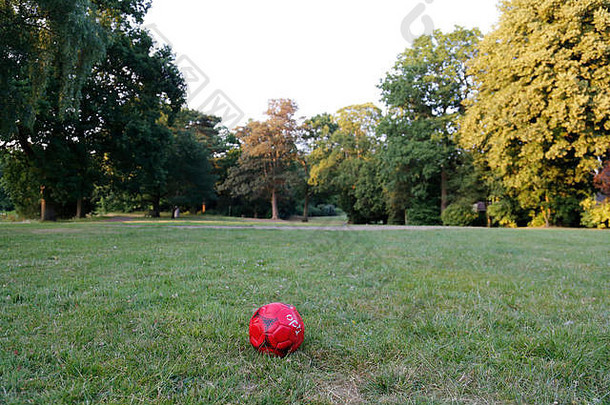 放气红色的足球被丢弃的公园