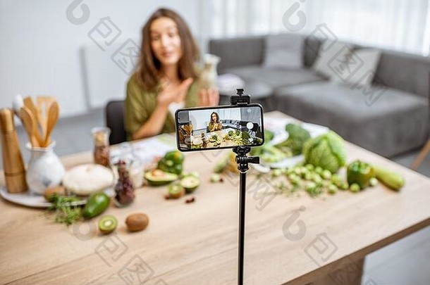 年轻的女人记录聪明的电话视频博客健康的吃坐着表格很多绿色素食主义者食物成分首页