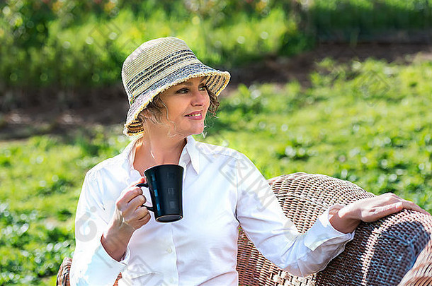 女人坐着花园持有杯<strong>咖啡</strong>