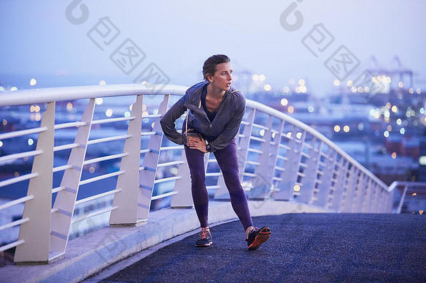 女跑步者伸展运动腿城市人行桥
