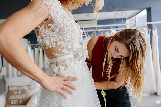 熟练的衣服设计师拟合婚礼礼服女人店里女人使调整新娘礼服时尚设计师工作室