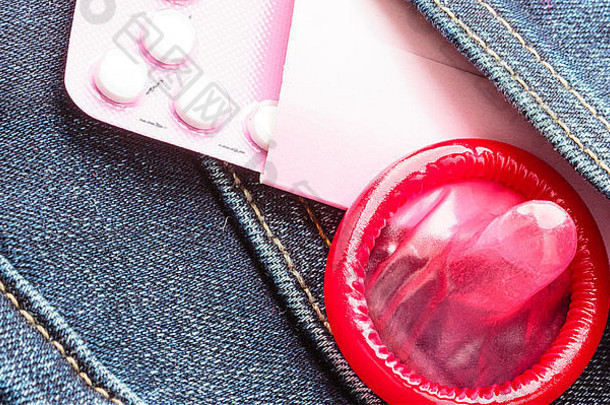医疗保健医学避孕出生控制特写镜头口服避孕药片红色的避孕套牛仔布口袋里背景