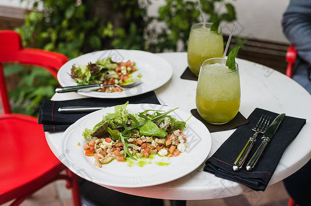 盘子新鲜的沙拉芝麻菜马苏里拉奶酪蔬菜西红柿鸡服务薄荷柠檬水小户外餐厅午餐