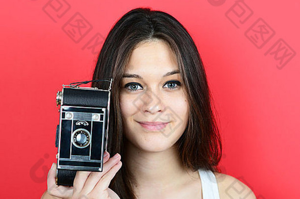 肖像年轻的女持有古董相机红色的背景