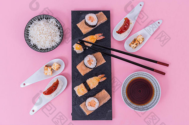 寿司卷集大马哈鱼鱼黑色的寿司董事会视图传统的亚洲厨房粉红色的背景