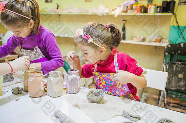 年轻的艺术家女孩绘画刷粘土花瓶表格陶瓷工作室