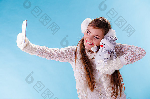 微笑漂亮的可爱的女人持有雪人采取自拍照片图片相机有吸引力的女孩耳罩