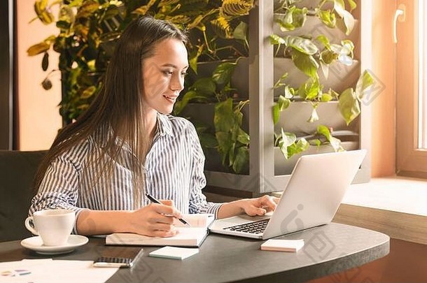 年轻的女人使笔记浏览移动PC咖啡馆