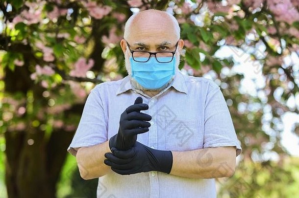 老年人风险受感染的免疫系统有效的战斗感染老高级男人。穿脸面具手套在户外高级公民